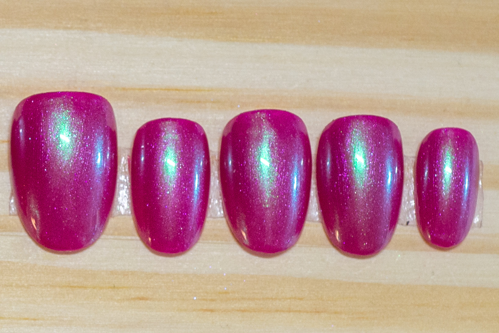 Berry pink press-on nails with a subtle light blue chrome overlay on a pink card
