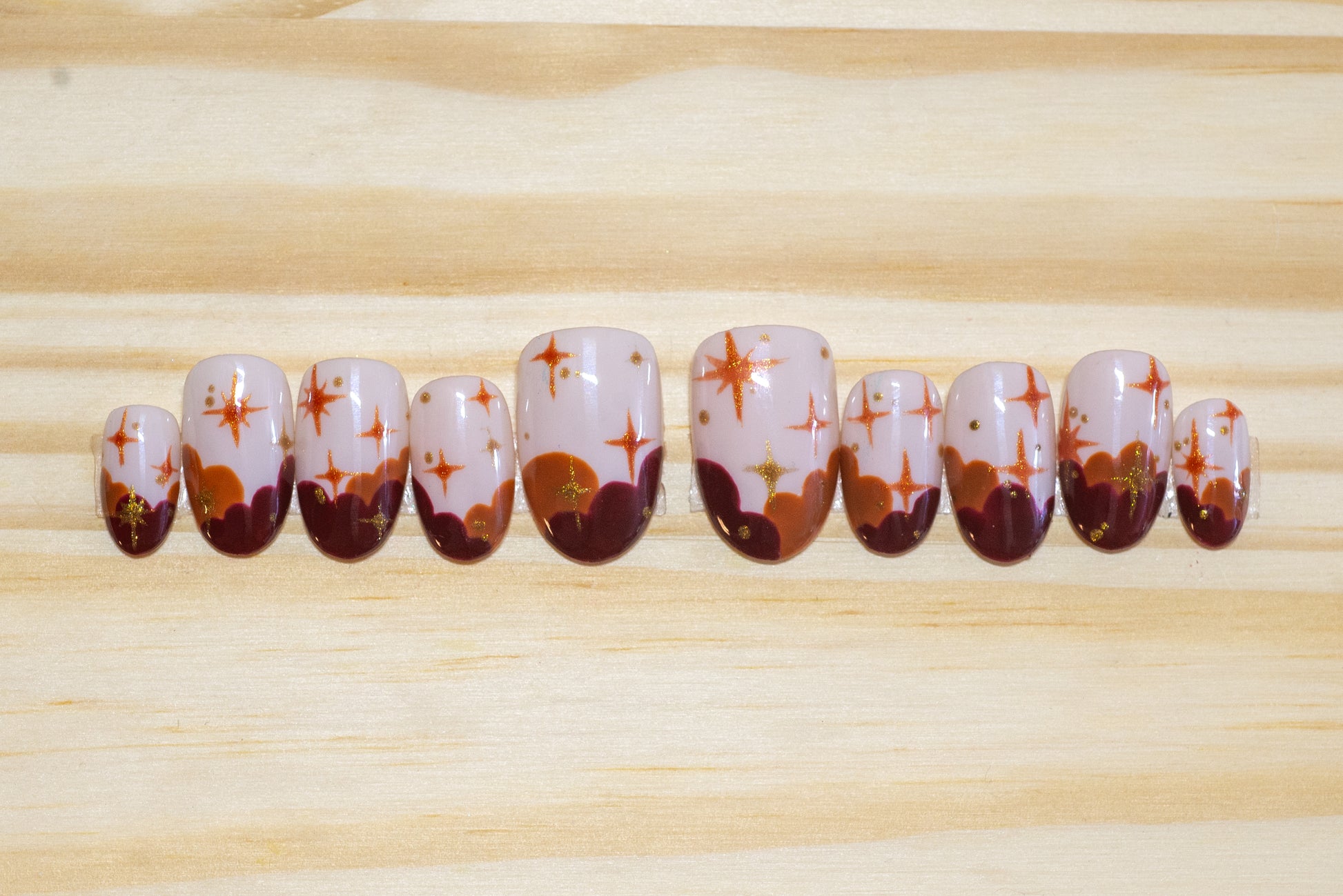 Press on nails in sunset colors with stars on a wooden background