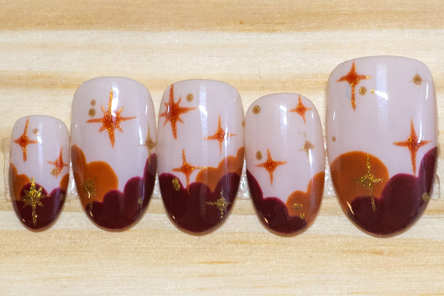 Press on nails in sunset colors with stars on a wooden background