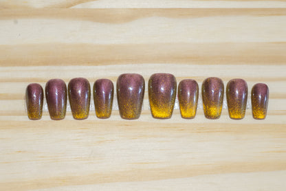 press on nails painted with a tiger-eye colored cat eye polish featured on a wooden background