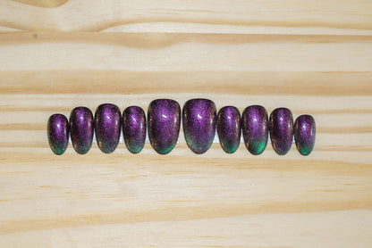 Cat eye press on nails in purple/fuchsia with teal green french tip flash on a wooden background