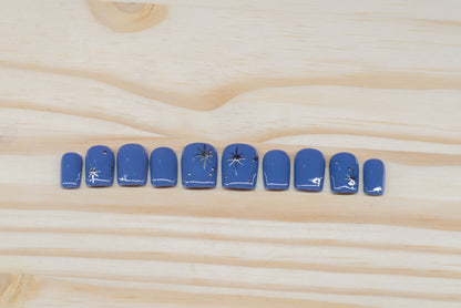 twilight blue press on nails with elegant silver chrome star motif featured on a wooden background