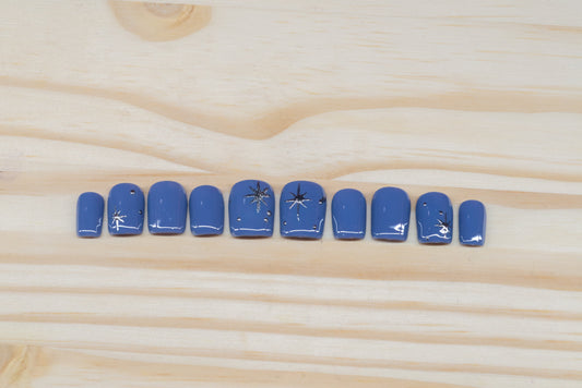 twilight blue press on nails with elegant silver chrome star motif featured on a wooden background