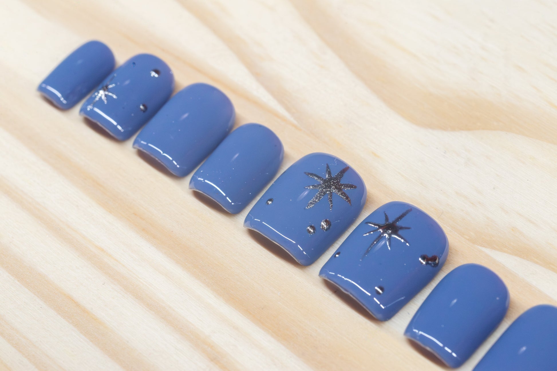 twilight blue press on nails with elegant silver chrome star motif featured on a wooden background
