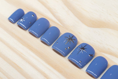 twilight blue press on nails with elegant silver chrome star motif featured on a wooden background