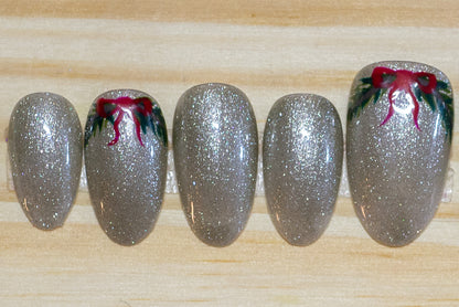 sparkly silver press on nails with  green wreath/swag and red bow detail on 4 nails on a wooden background